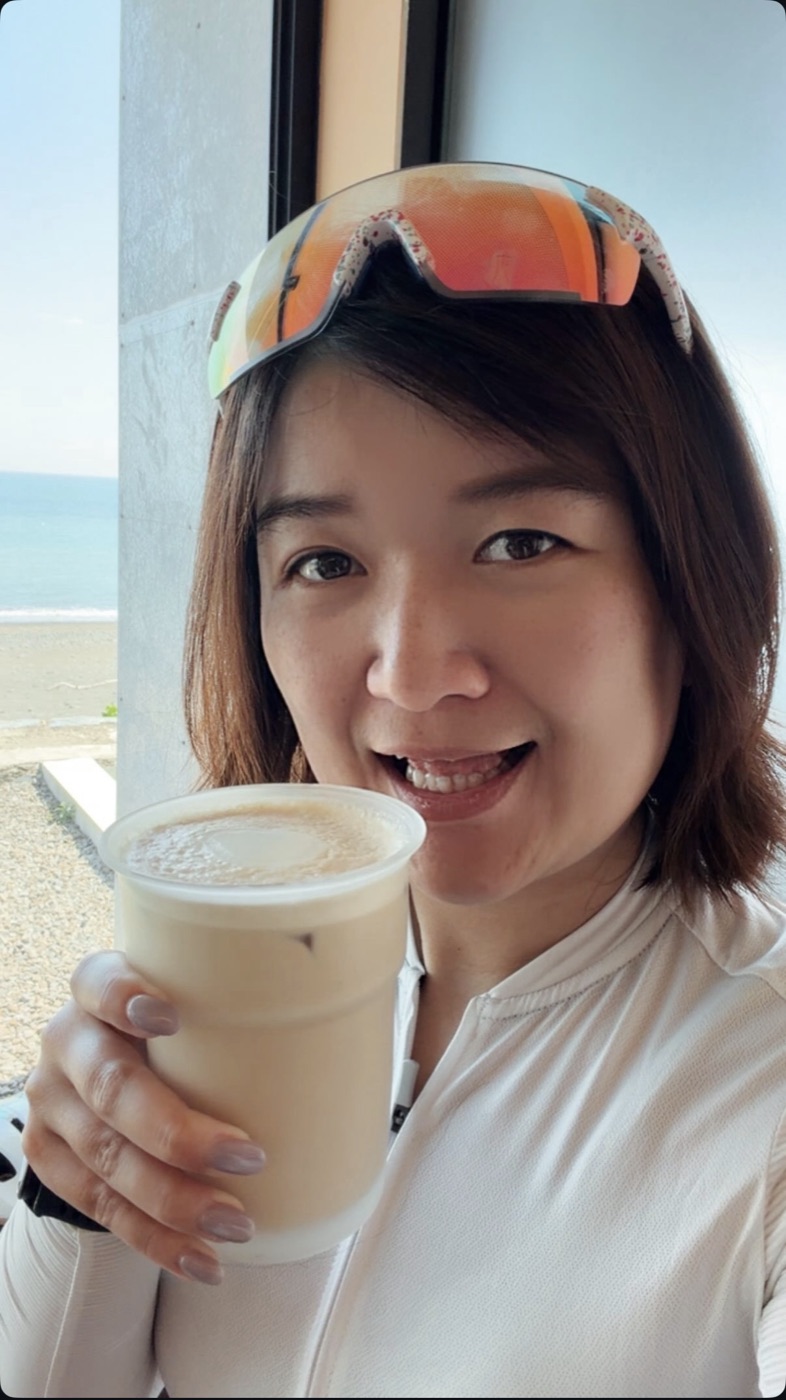 夏夏在海邊的咖啡廳，手拿一杯咖啡笑著自拍