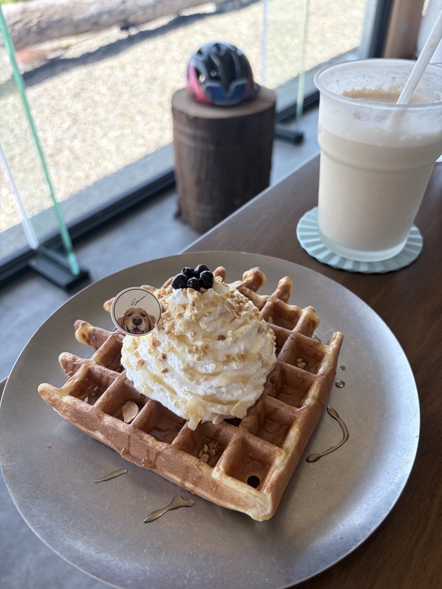 咖啡廳桌上的鬆餅和一杯奶茶，窗邊放著單車安全帽