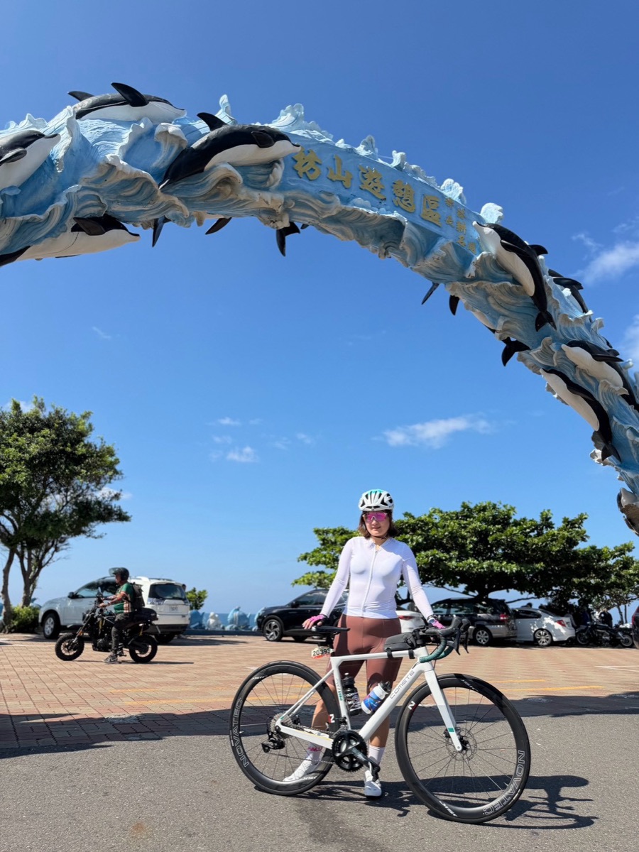 夏夏牽著單車站在海豚拱門下